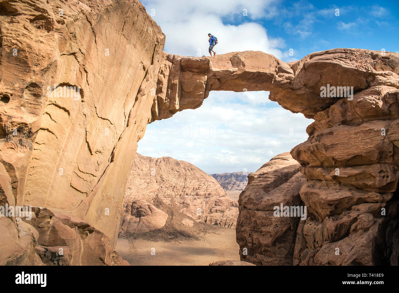 Hombre caminando a través de un puente de piedra, Wadi Rum, Jordania Foto de stock