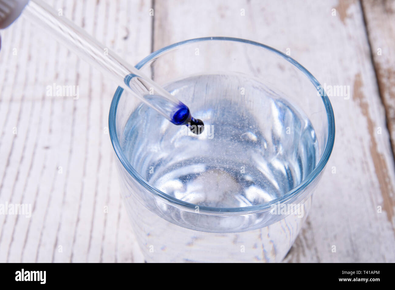 Pipeta con tinta azul en un vaso de agua en la madera blanca Fotografía de  stock - Alamy