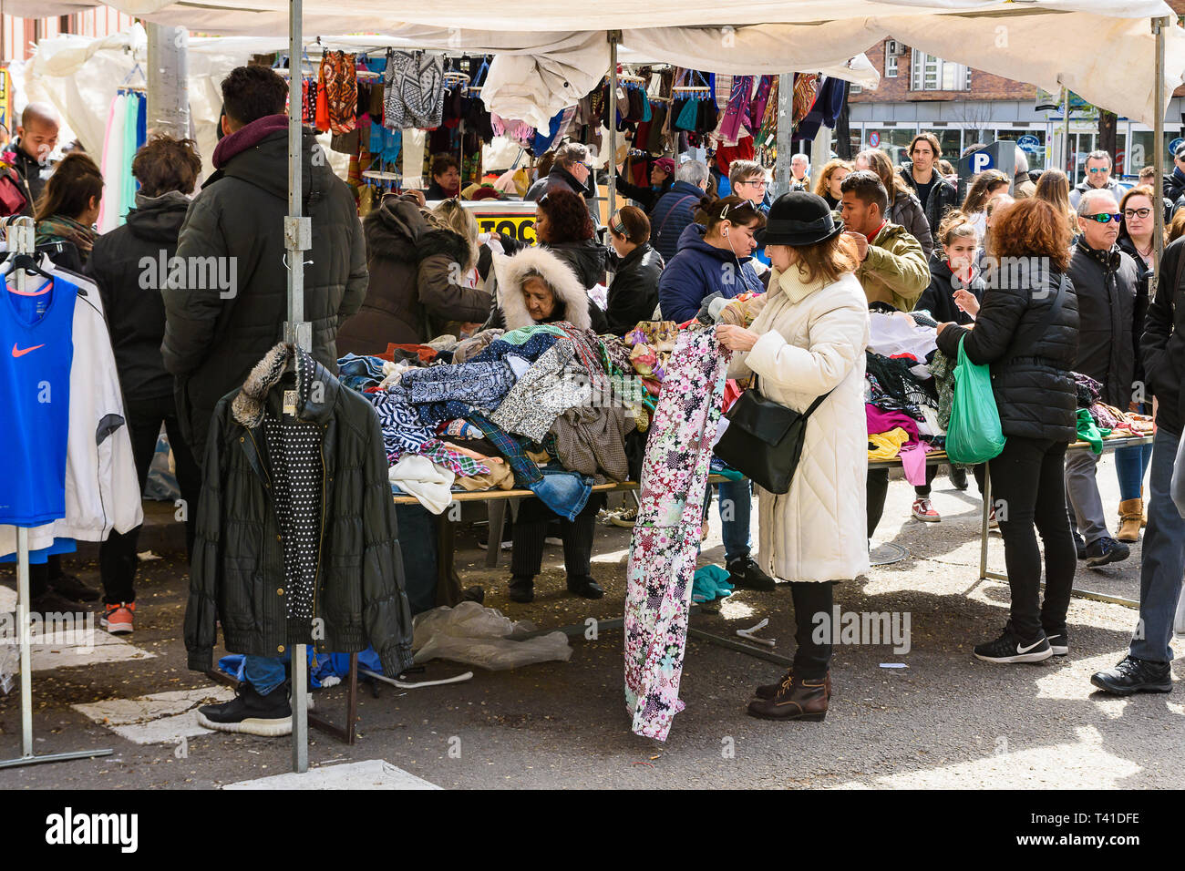 Madrid, España. 7 abr, 2019. El Rastro de Madrid. Una mujer elige la ropa  en el mercado de la calle en Madrid Fotografía de stock - Alamy