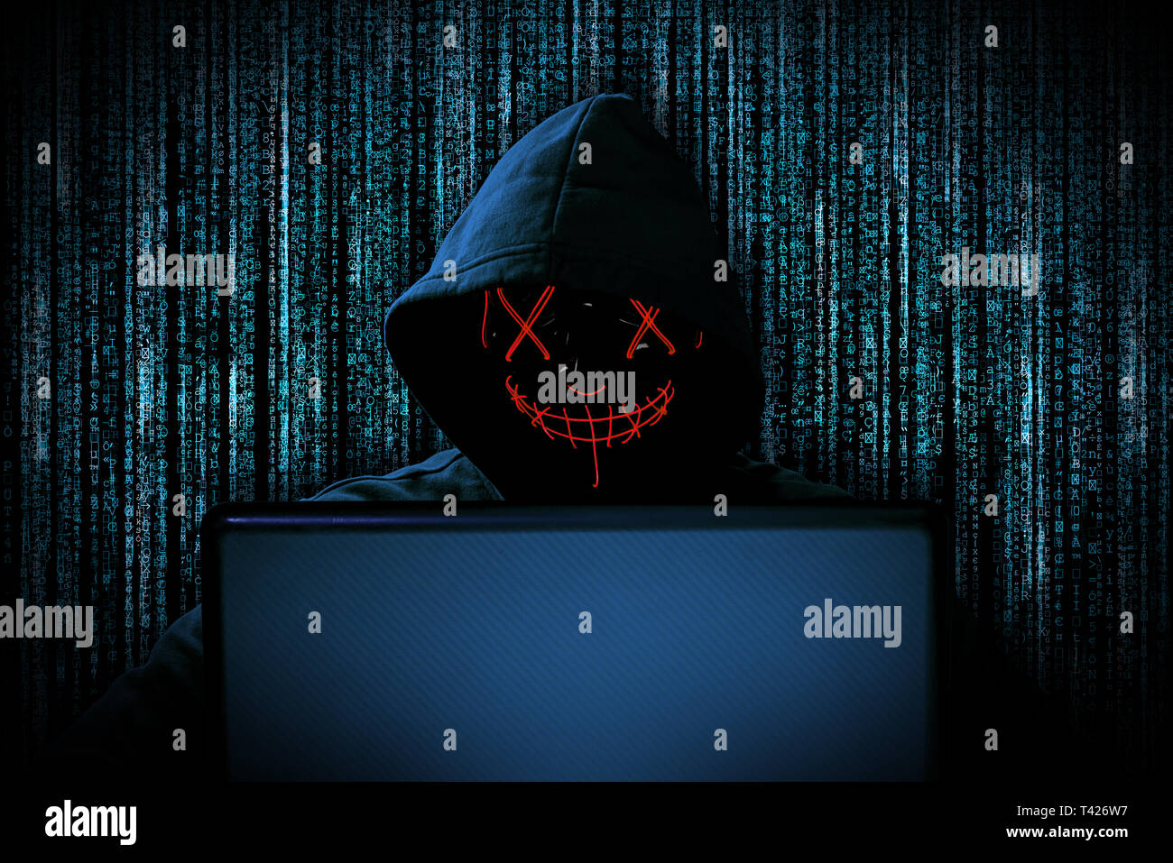 Hacker con rojo brillante detrás de la máscara para ordenador portátil delante de fuente azul de fondo código binario internet cyber ataque hack concepto de ordenador Foto de stock