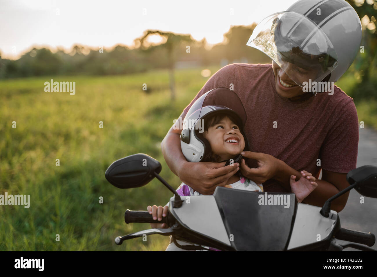 Daddy ayudar a su hija a abrochar el casco mientras viajaba en una moto  scooter Fotografía de stock - Alamy