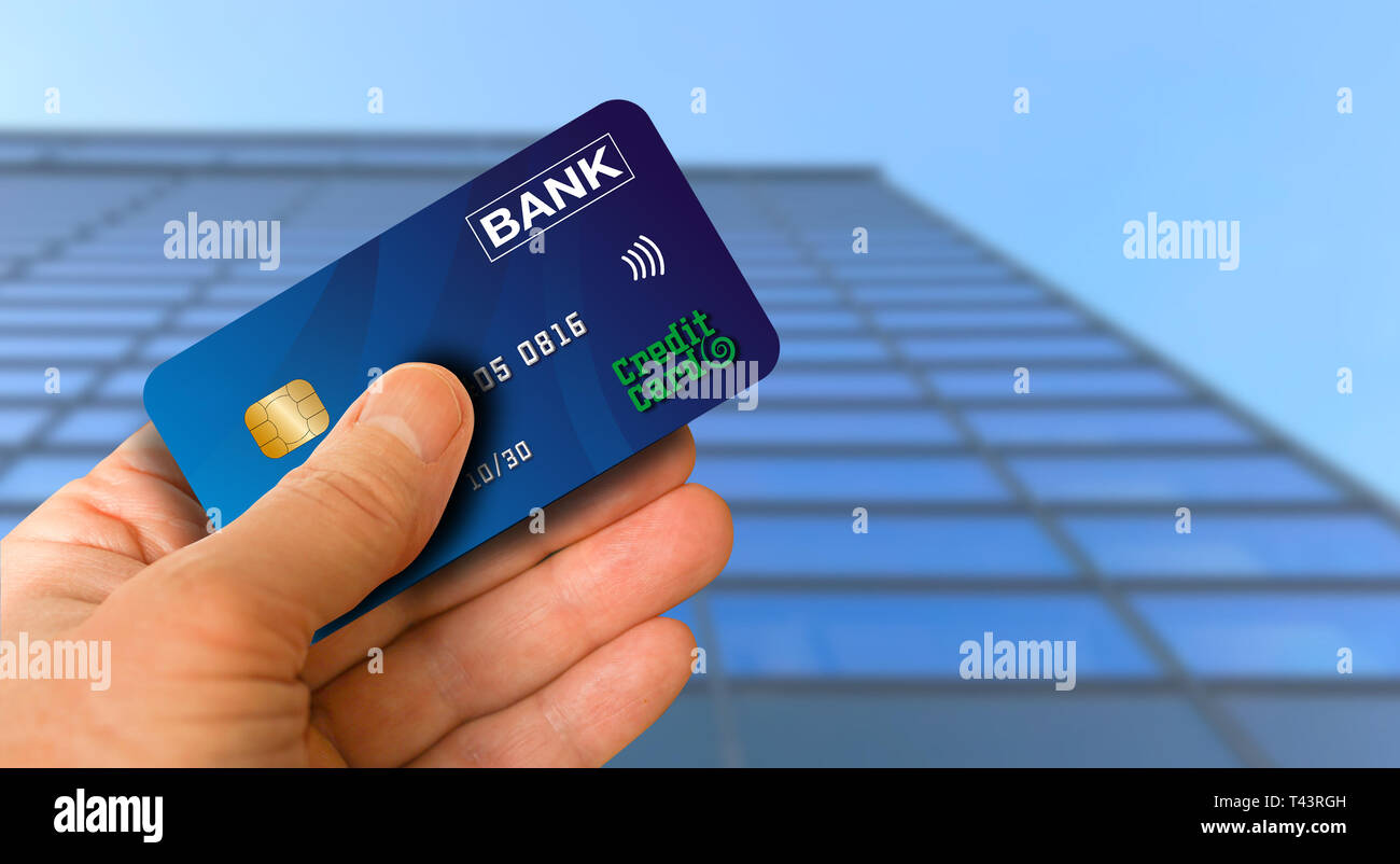 Tarjeta de crédito en la mano que sujeta el aire delante de una moderna oficina edificio alto de vidrio. Cerca de la mano y tarjeta con fondo de cielo azul. Foto de stock