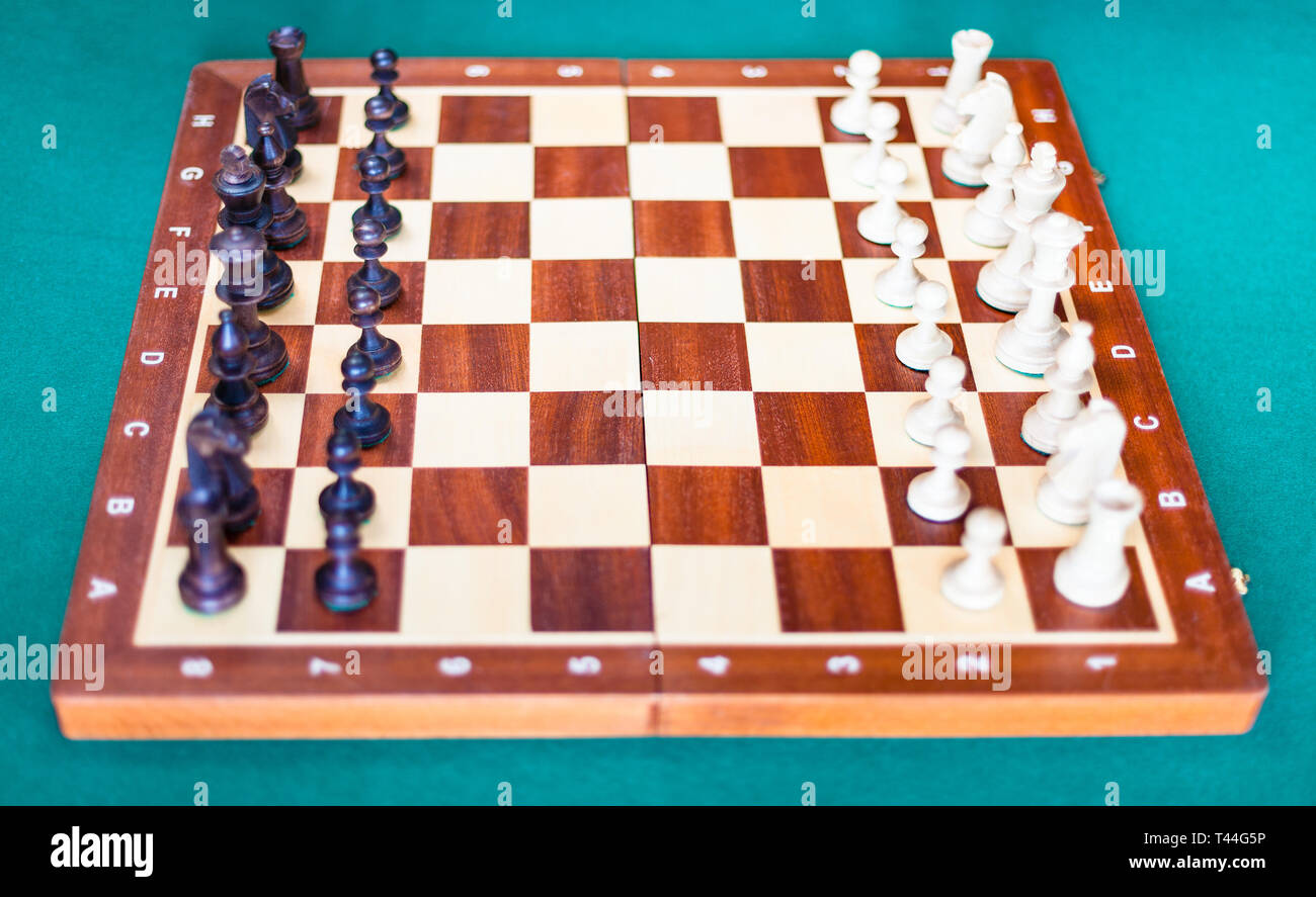 Tablero de madera con piezas de ajedrez en posición inicial sobre el tapete  verde mesa. Centrarse en el centro de la junta Fotografía de stock - Alamy