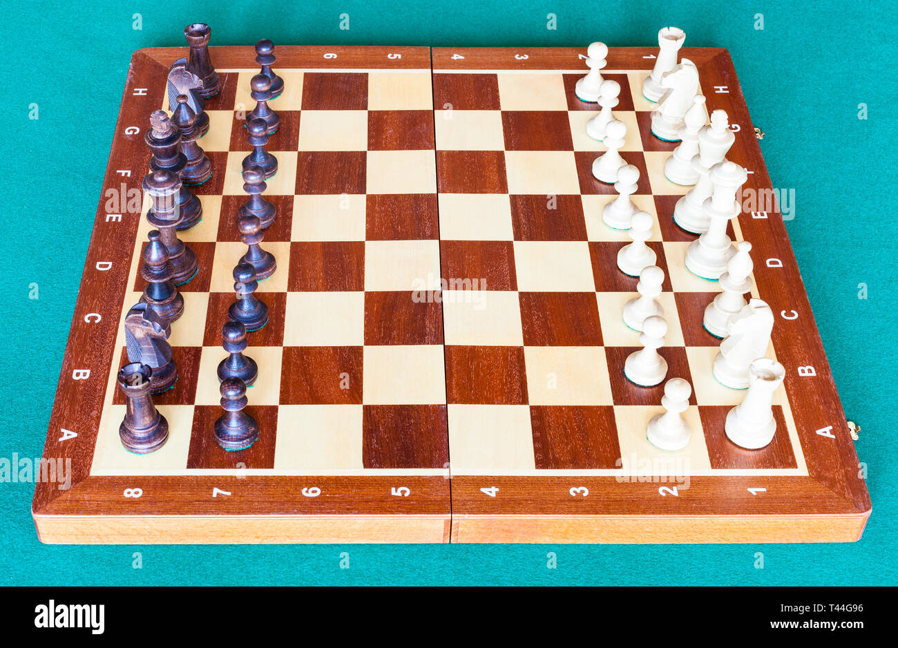 Vista lateral del tablero de ajedrez de madera con piezas de ajedrez en  posición inicial sobre el tapete verde tabla Fotografía de stock - Alamy