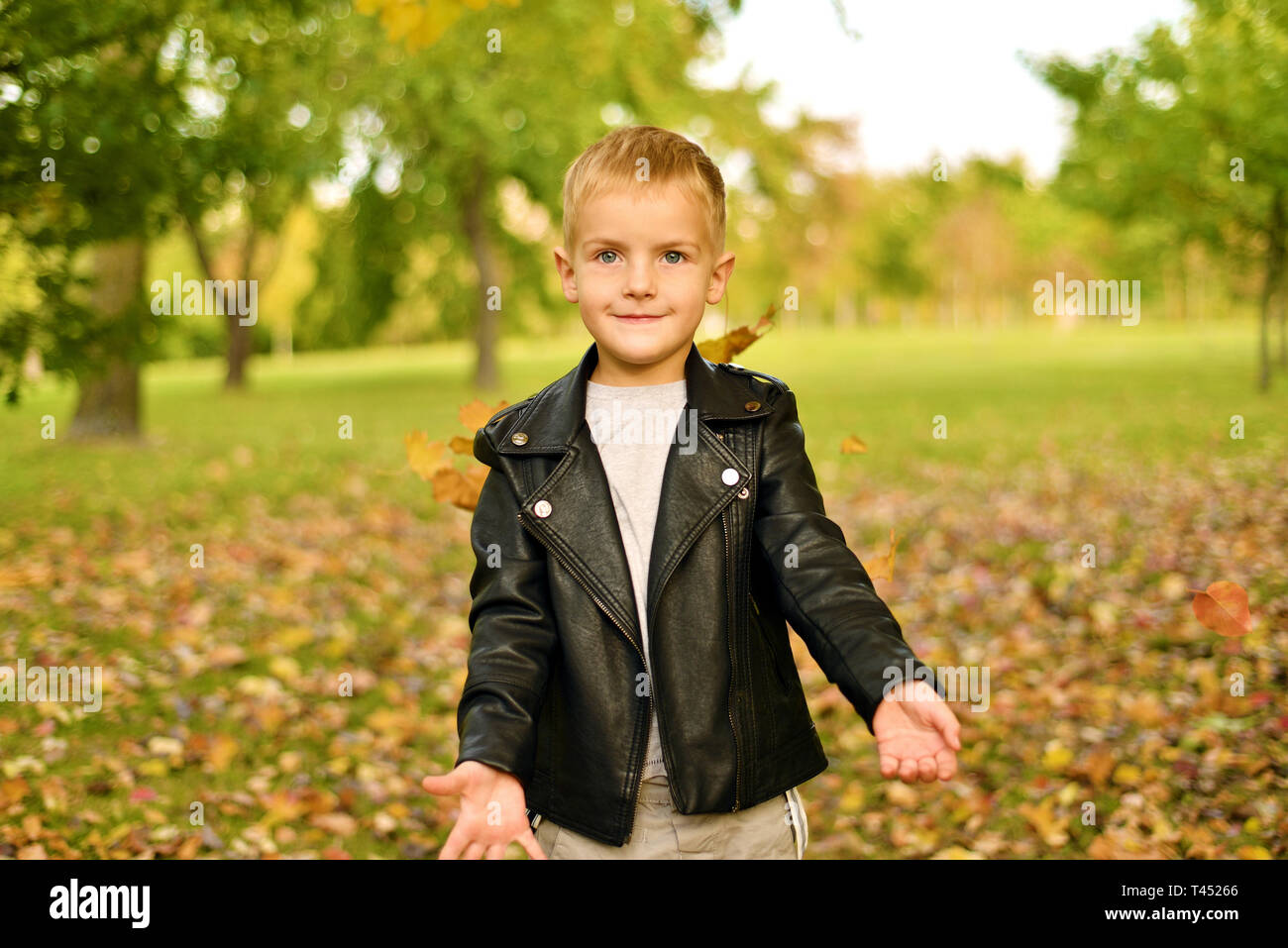 Otoño retrato cute little boy la chaqueta de cuero negro. bebé jugando y divirtiéndose en el parque Fotografía de stock Alamy