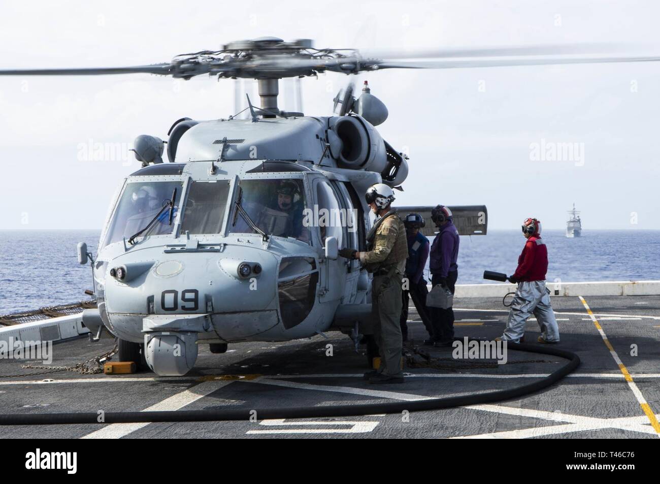 Océano Pacífico (11 de marzo, 2019) - Los marineros asignados al transporte anfibio dock buque USS Green Bay (LPD 20) combustible un SH-60 Sea Hawk helicóptero asignado a la Isla de los Caballeros de mar escuadrón de helicópteros de combate (HSC) 25 en la cubierta de vuelo durante un ejercicio de entrenamiento con otros buques de guerra de la Marina de los EE.UU. Los buques de guerra de la Marina de EE.UU. entrenan juntos para aumentar la habilidad táctica, la letalidad y la interoperabilidad de las unidades participantes en una época de gran potencia para la competencia. Foto de stock