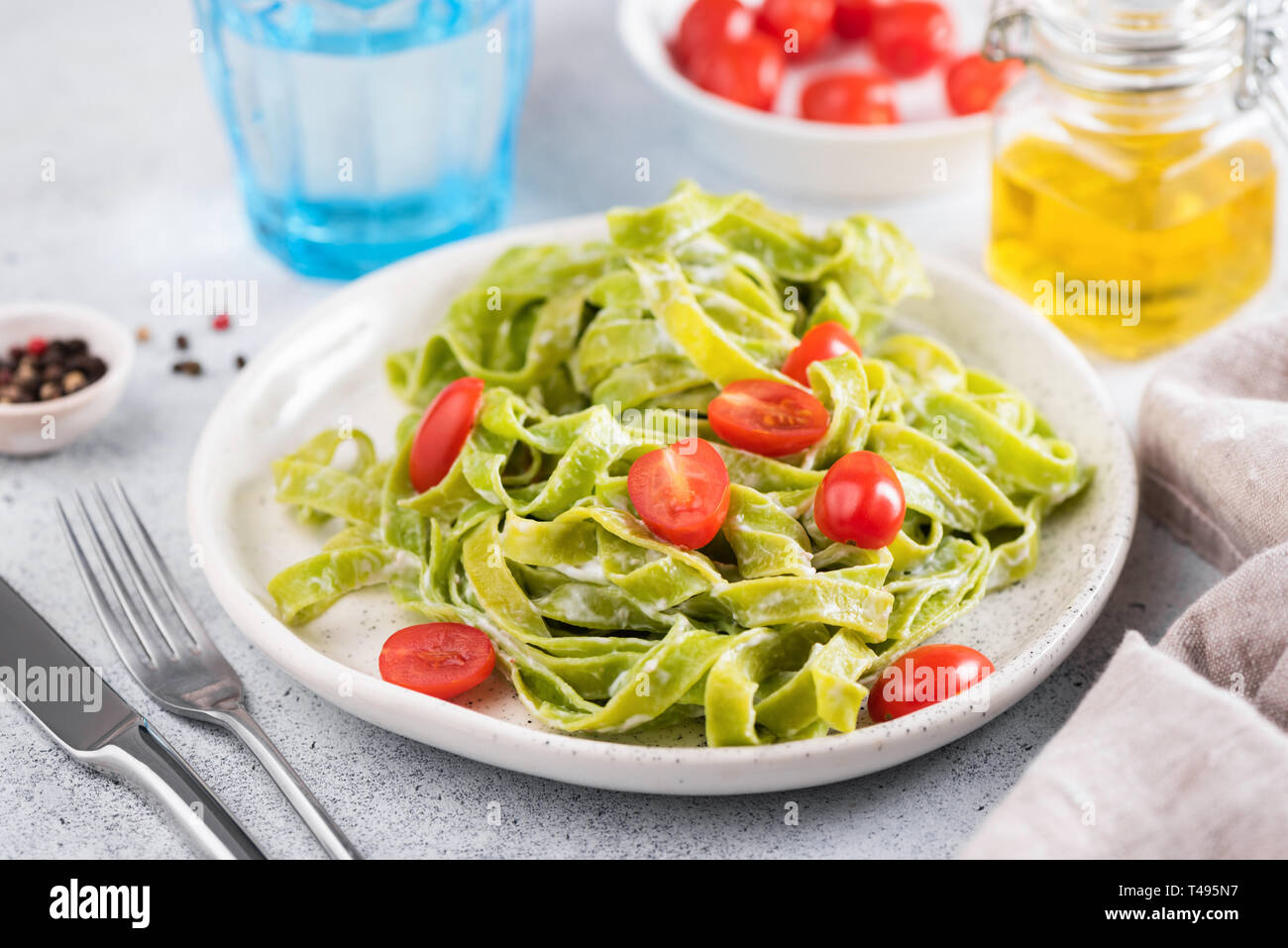 Espinaca verde pasta con salsa de crema y los tomates en un plato