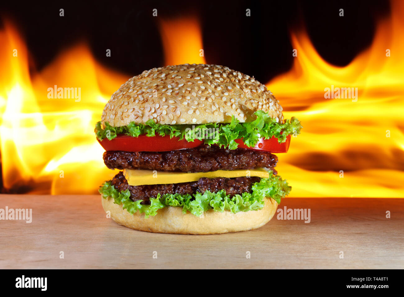 Gran hamburguesa con fuego real sobre un fondo Foto de stock