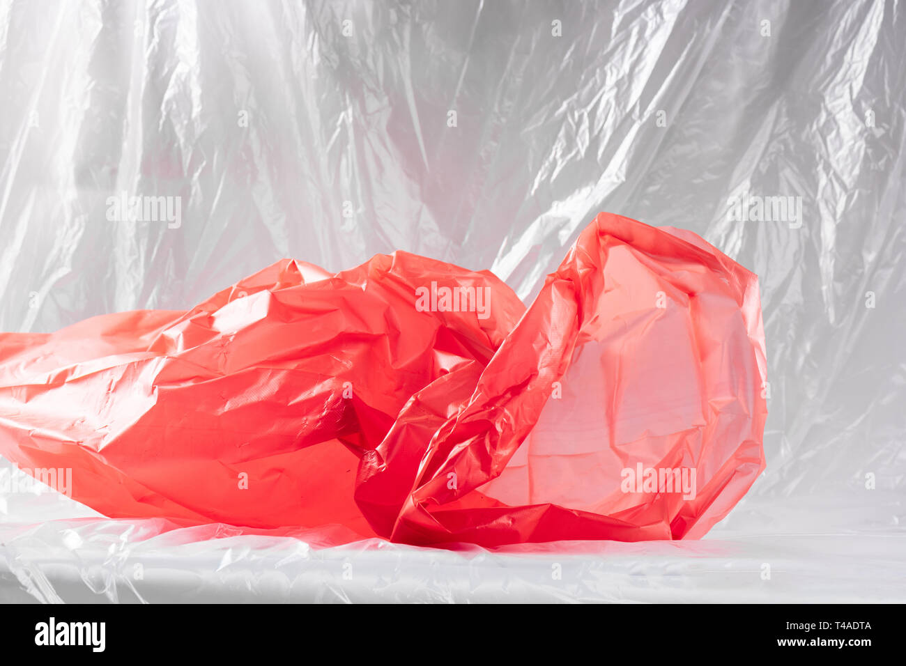 Repugnante arrugado paquete de basura de plástico rojo presentando el estado de nuestra naturaleza Foto de stock