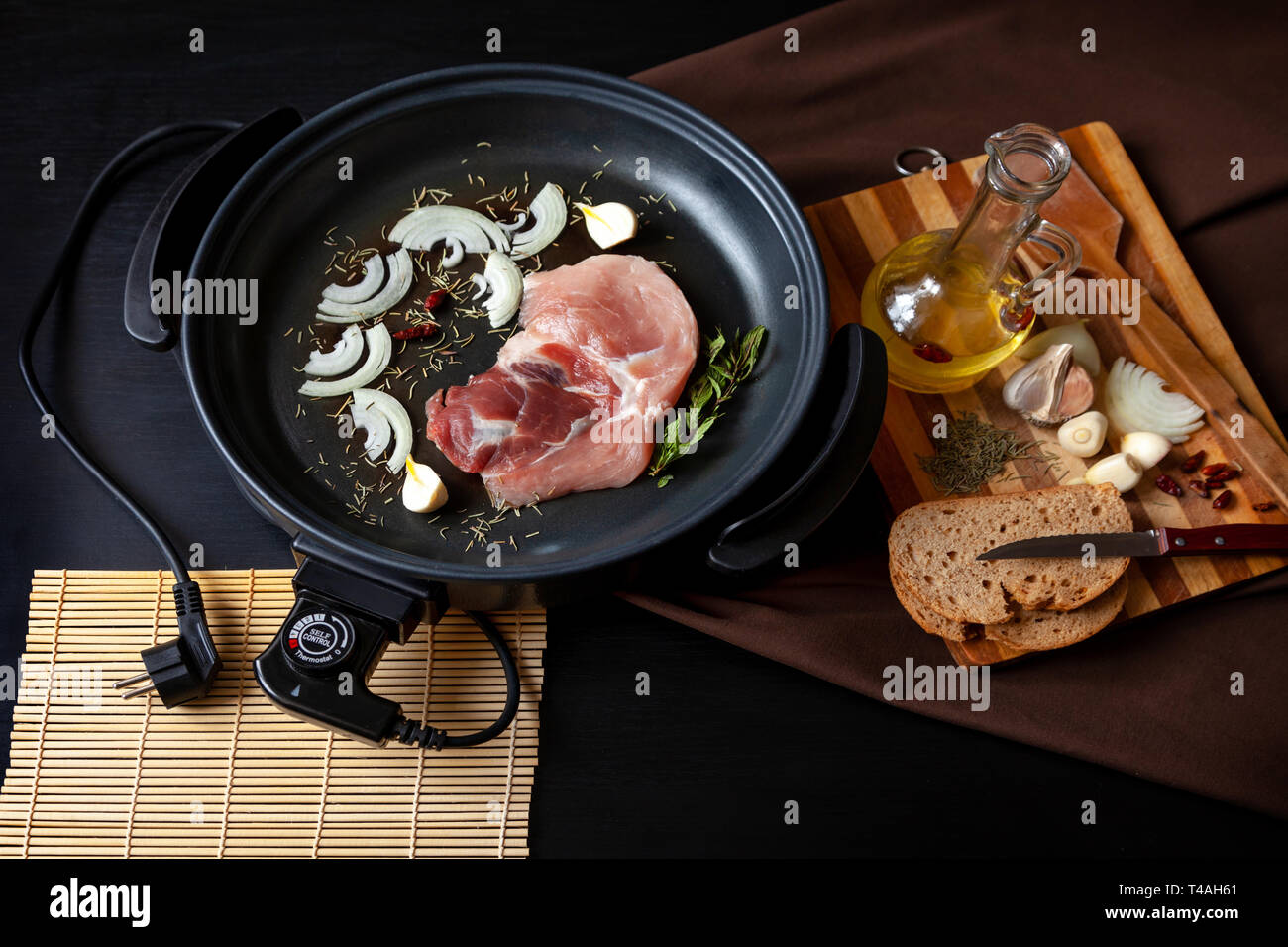 Sartén eléctrica con carne de cerdo en la mesa. Auxiliar independiente la  sartén para cocinar en cualquier lugar Fotografía de stock - Alamy