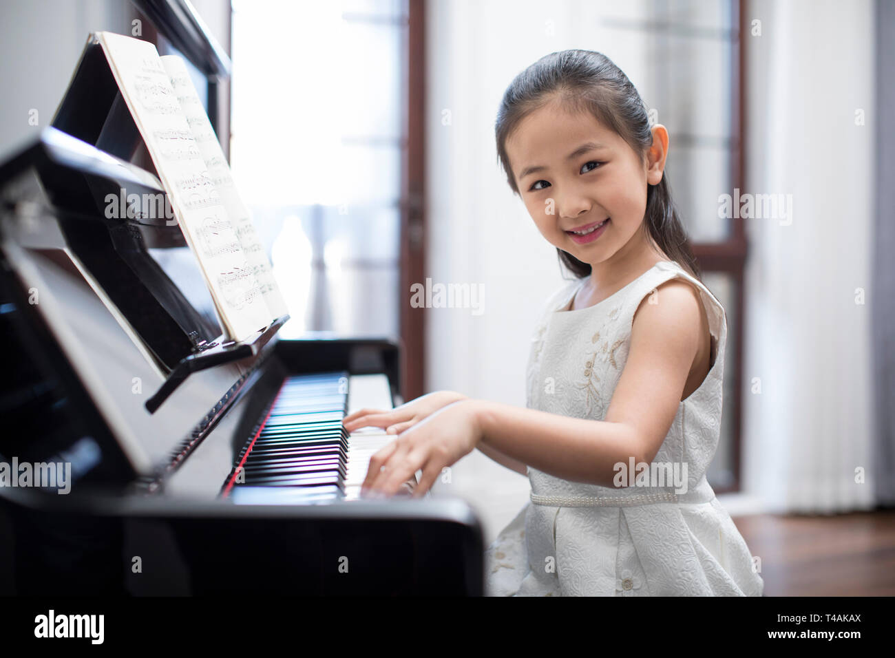 Feliz niña tocando el piano Fotografía de stock - Alamy