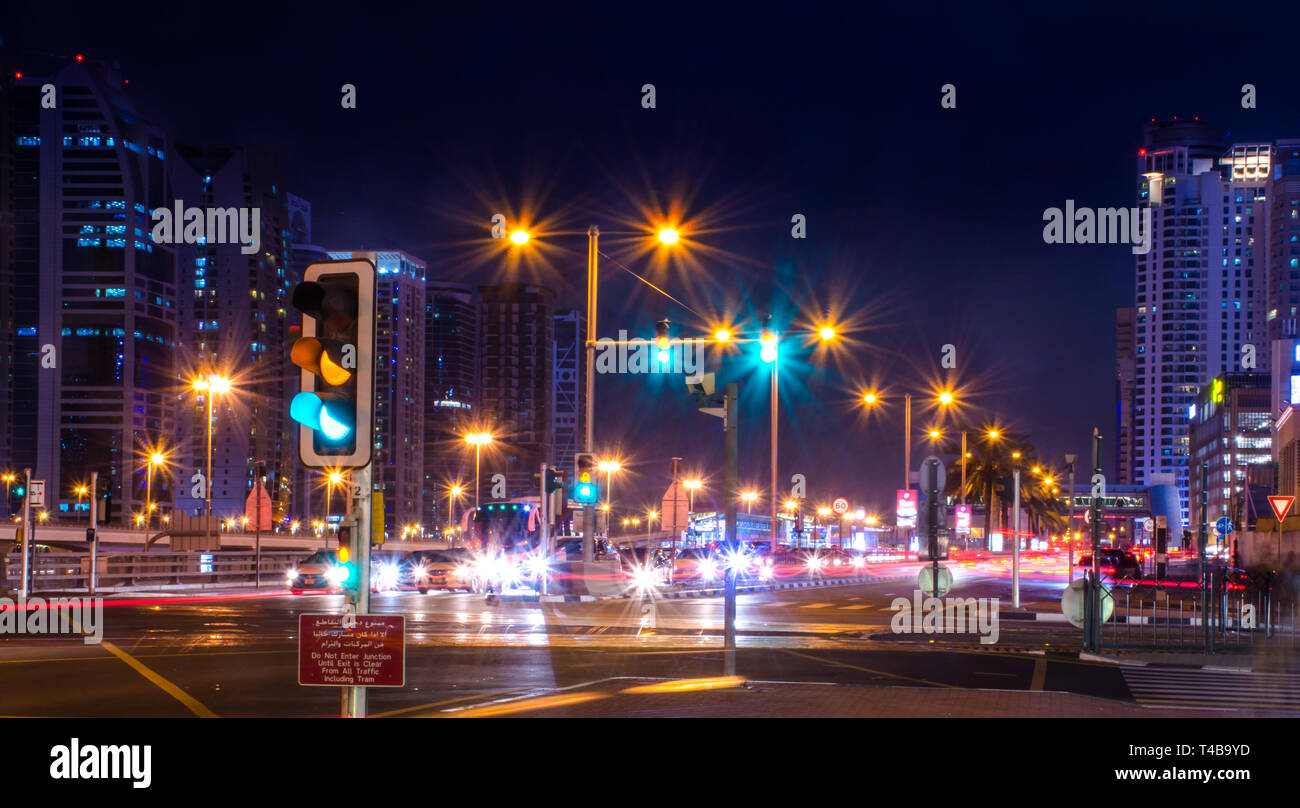 Coloridas luces de señales de tráfico en la ciudad de Dubai, hermosa vista nocturna de la estación de Metro de Dubai y los edificios el cielo azul con las luces de la calle Foto de stock