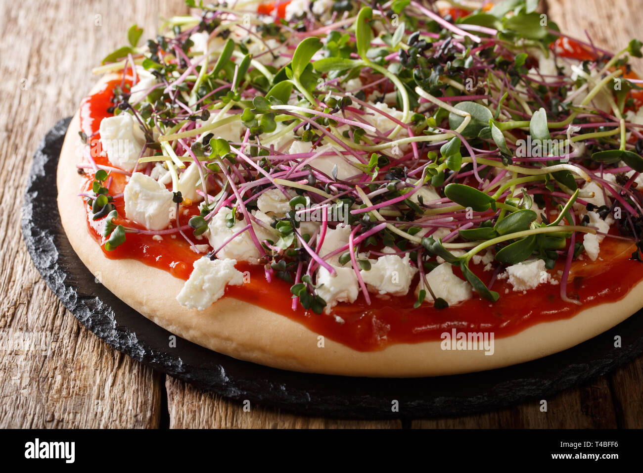 Dieta pizza vegetariana con queso feta y micro mix fresco verde de cerca en la tabla horizontal. Foto de stock