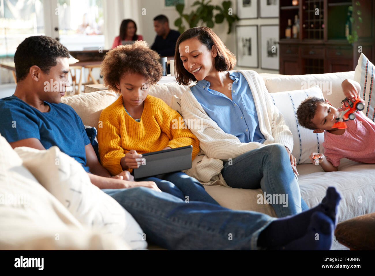 Tres generaciones de la familia la familia pasar tiempo en casa en su salón, los padres y los niños en el primer plano, los abuelos en el fondo, el enfoque selectivo Foto de stock