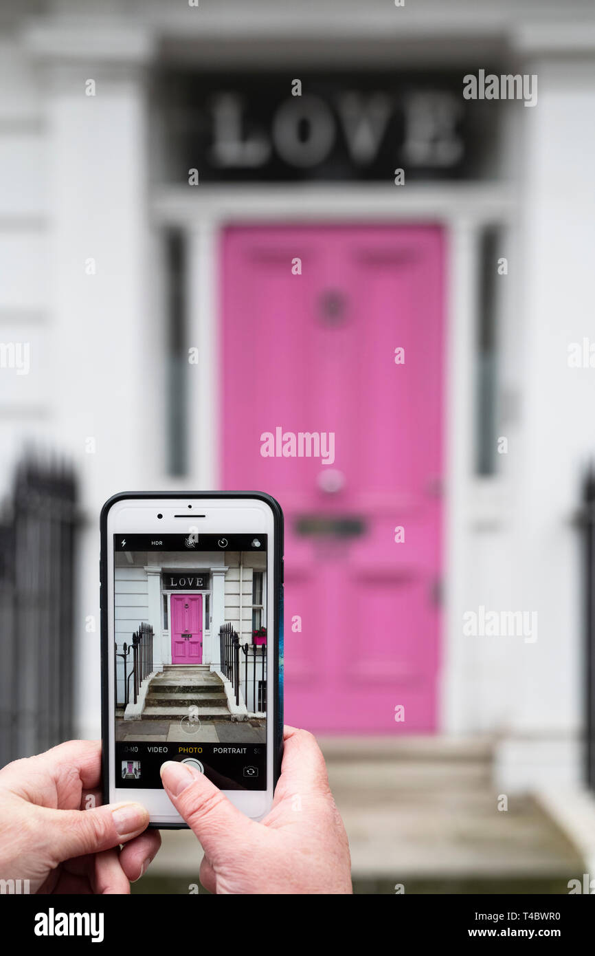 Tomar una foto en un iPhone de una casa rosa puerta delantera con amor en la ventana en Oakley Street, Kensington y Chelsea, Londres, Inglaterra Foto de stock