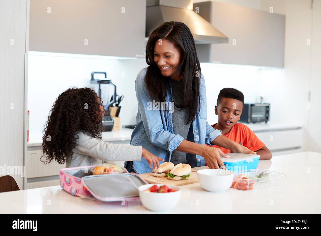 Los niños en la cocina en casa ayudando a la madre a hacer almuerzo saludable Foto de stock