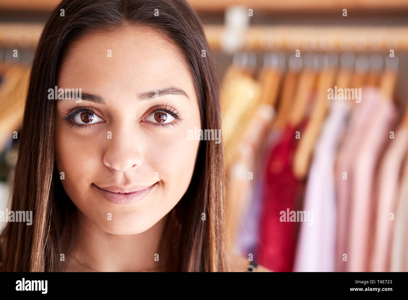Retrato de mujer cliente o propietario de pie por bastidores de ropa en tienda de moda independiente Foto de stock