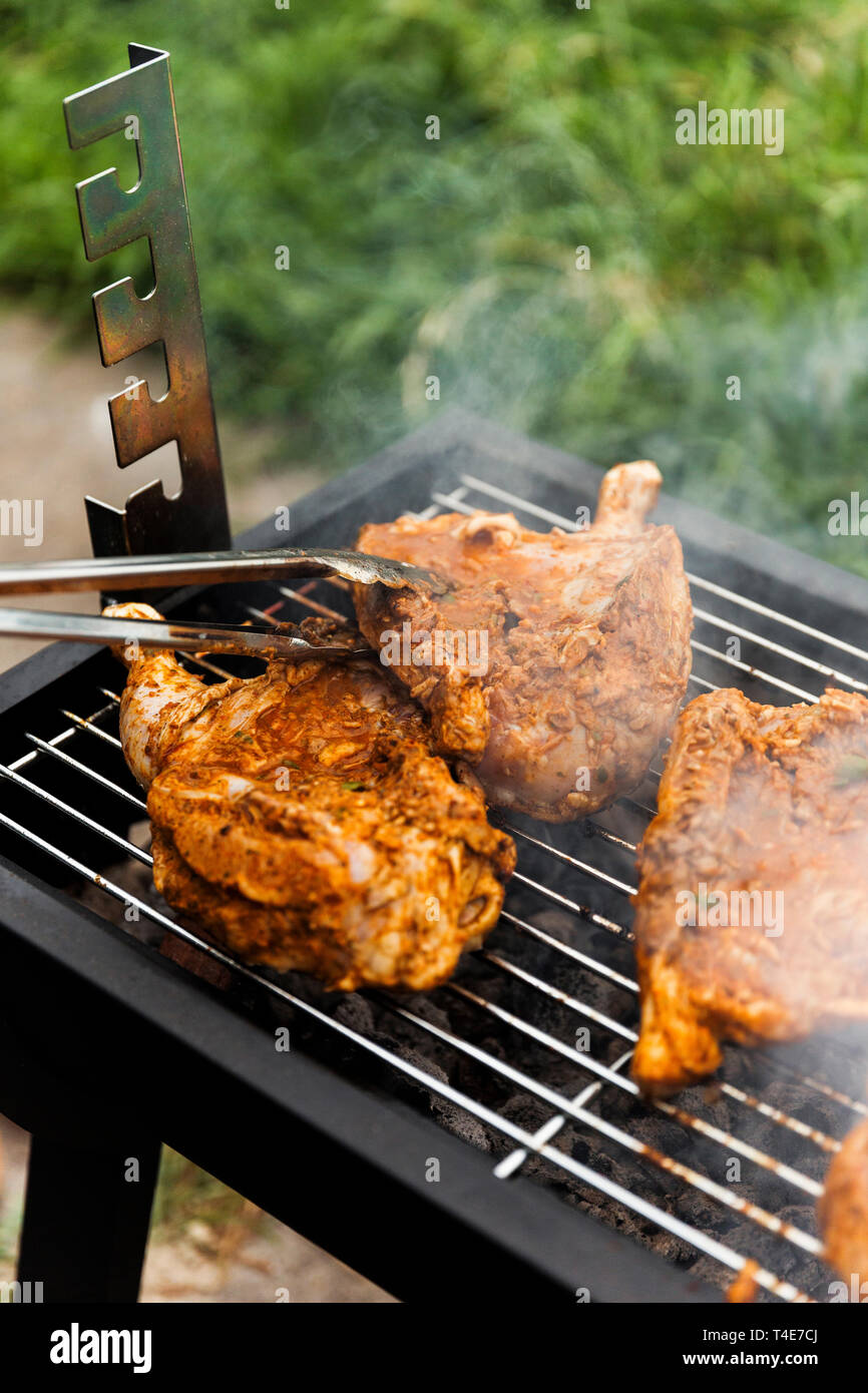 Voltear el pollo a cocinar lado restante en el pequeño patio de atrás de la parrilla. Foto de stock