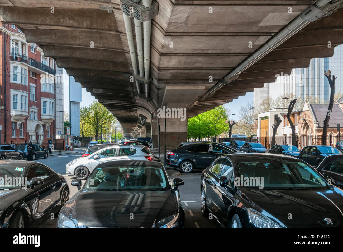 Los automóviles estacionados bajo el paso elevado de Hammersmith. Construido en 1960, el paso elevado lleva la carretera A4 en el oeste de Londres. Foto de stock
