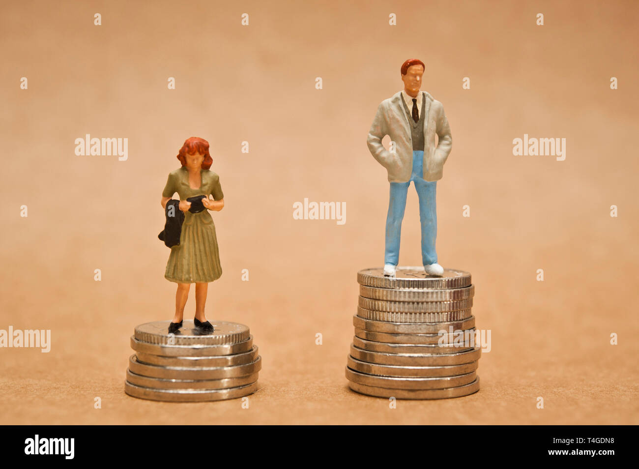 El hombre y la mujer en pie de figurillas en monedas, la brecha salarial entre los géneros concepto Foto de stock