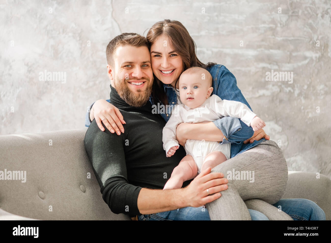 Familia feliz con el bebé sentarse en el sofá Foto de stock