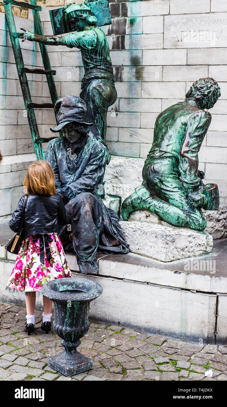 Amberes, Bélgica. Ejecutante de la calle fingiendo ser una estatua. Una niña va a hablar a la mujer vestida como estatua Foto de stock