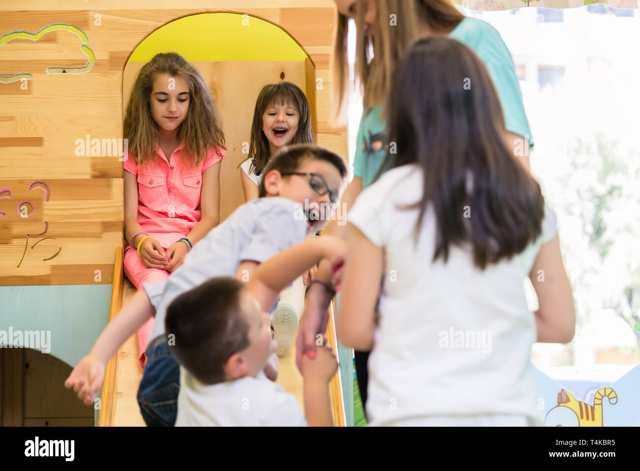 Cute chicas sonrientes durante Juegos vigilados en un moderno jardín de infantes Foto de stock