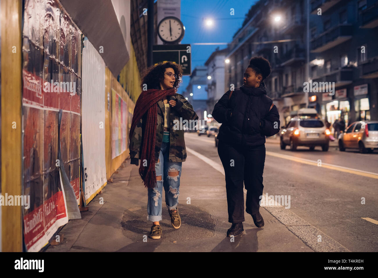 Dos morena y rizado chicas caminando en la calle conversating -, la interacción comunicativa, alegre Foto de stock