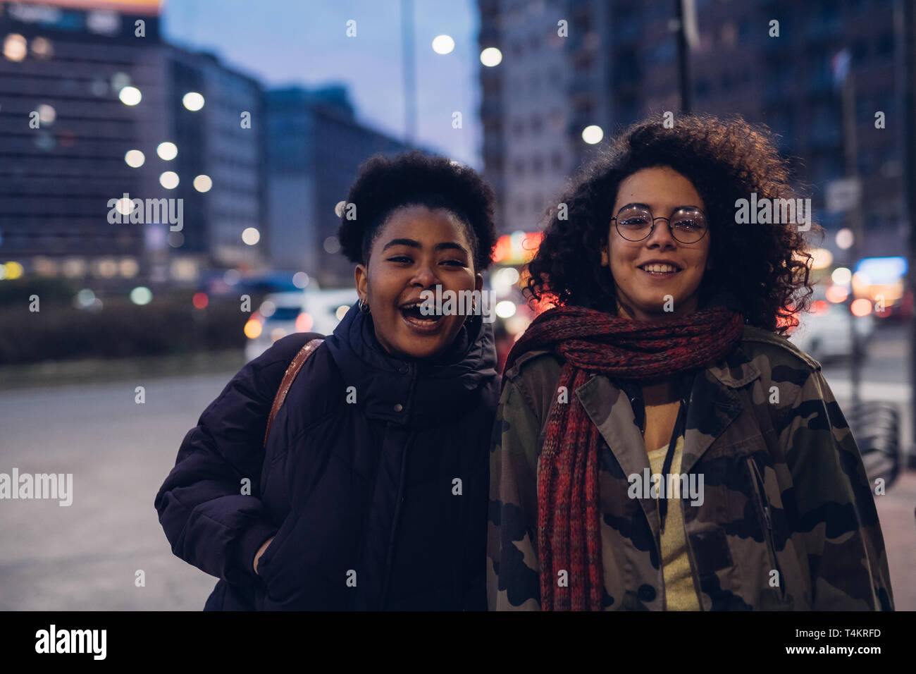 Dos niñas rizado feliz en la ciudad, sonriendo y mirando a la cámara - natural, el realismo, la amistad Foto de stock