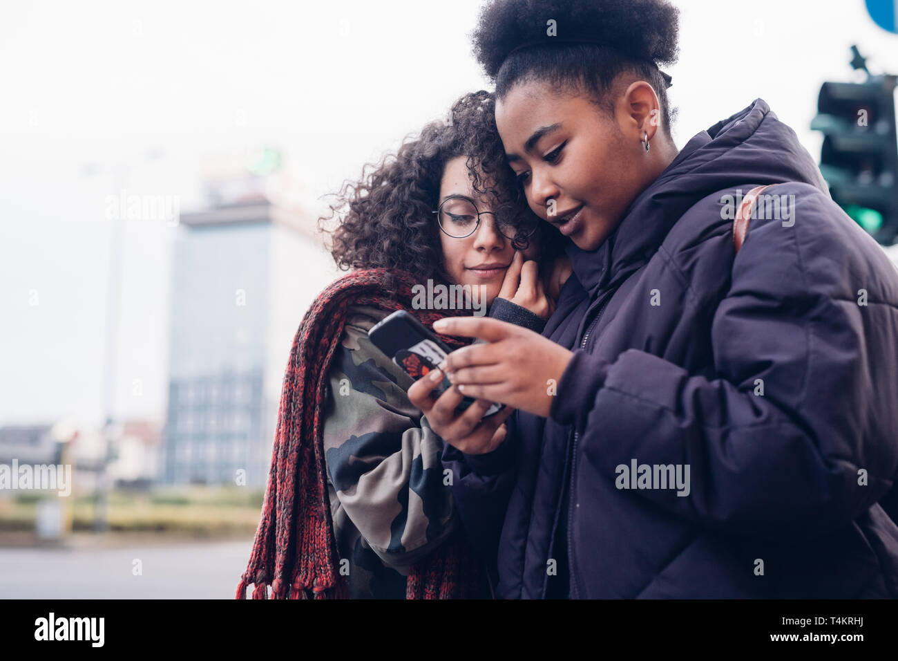 Dos jóvenes curly negras usando el smartphone a la ciudad - interacción, conexión curiosidad Foto de stock