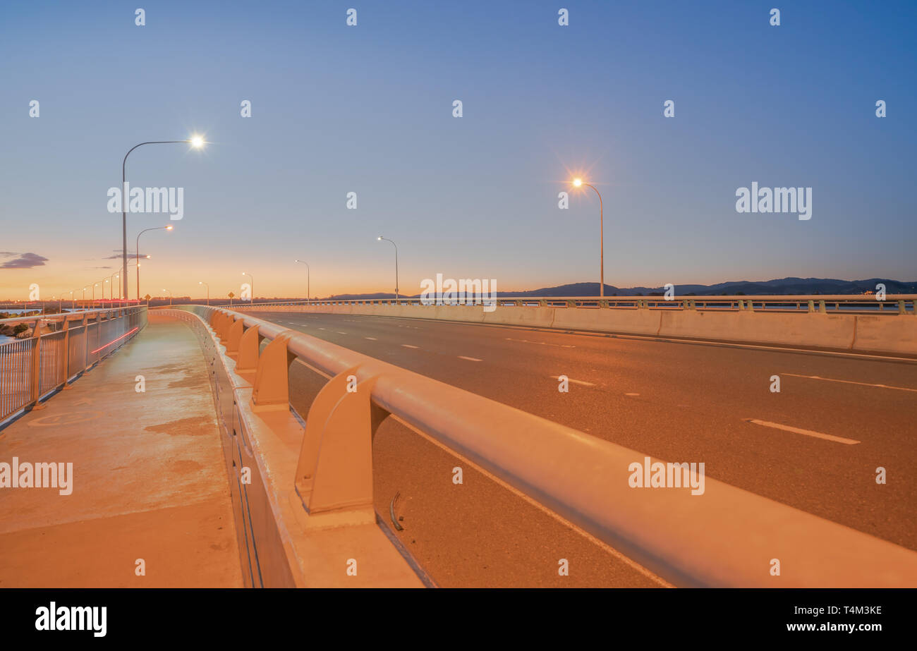 El Puerto de Tauranga Puente ruta de transporte por carretera y vía peatonal y ciclista con resplandor de ciclistas y pasando las luces del vehículo Foto de stock
