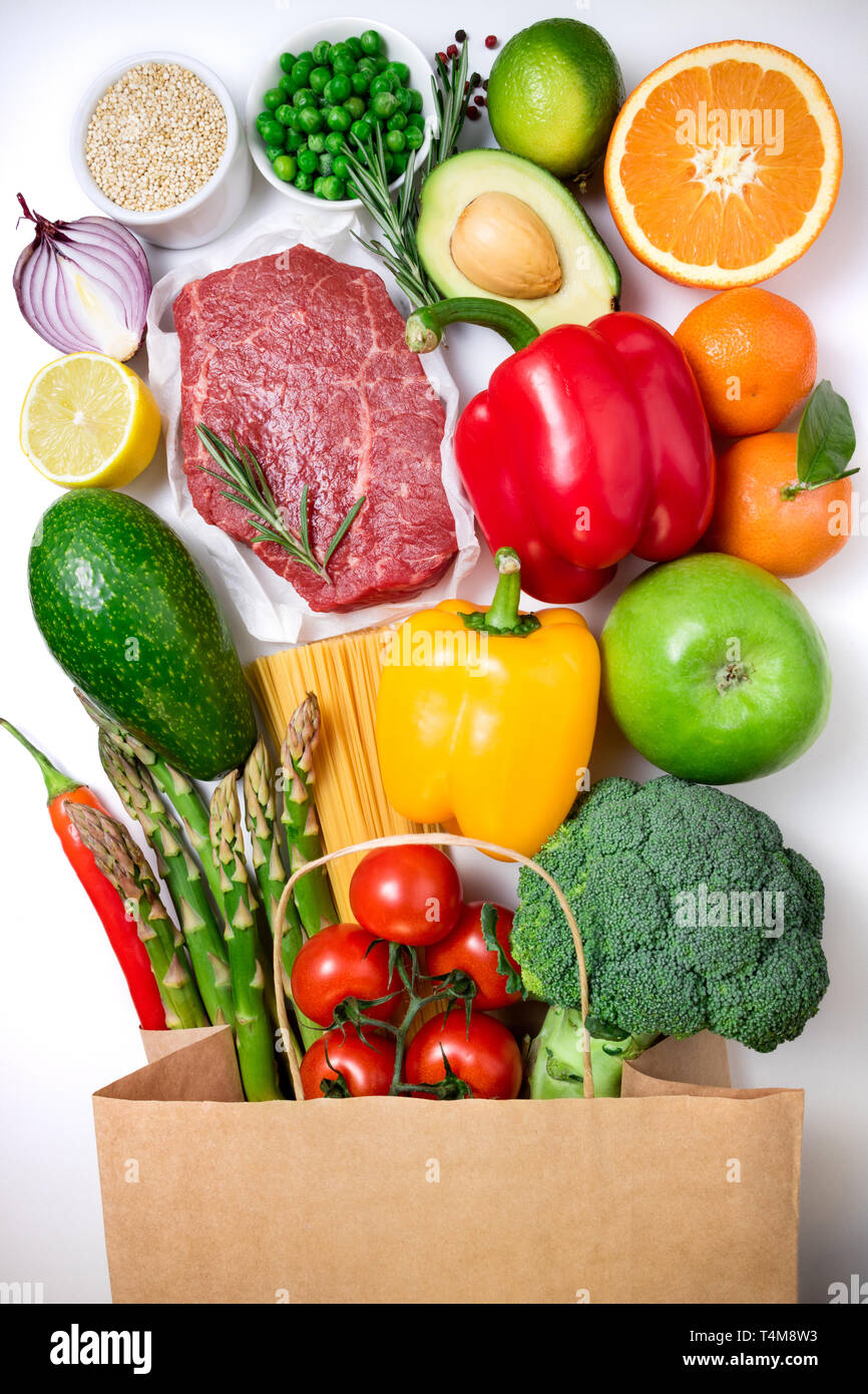Fondo de alimentos saludables. Alimentos saludables en la bolsa de papel de carne, frutas, verduras y pasta sobre fondo blanco. Concepto de supermercado de compras. Vista superior Foto de stock