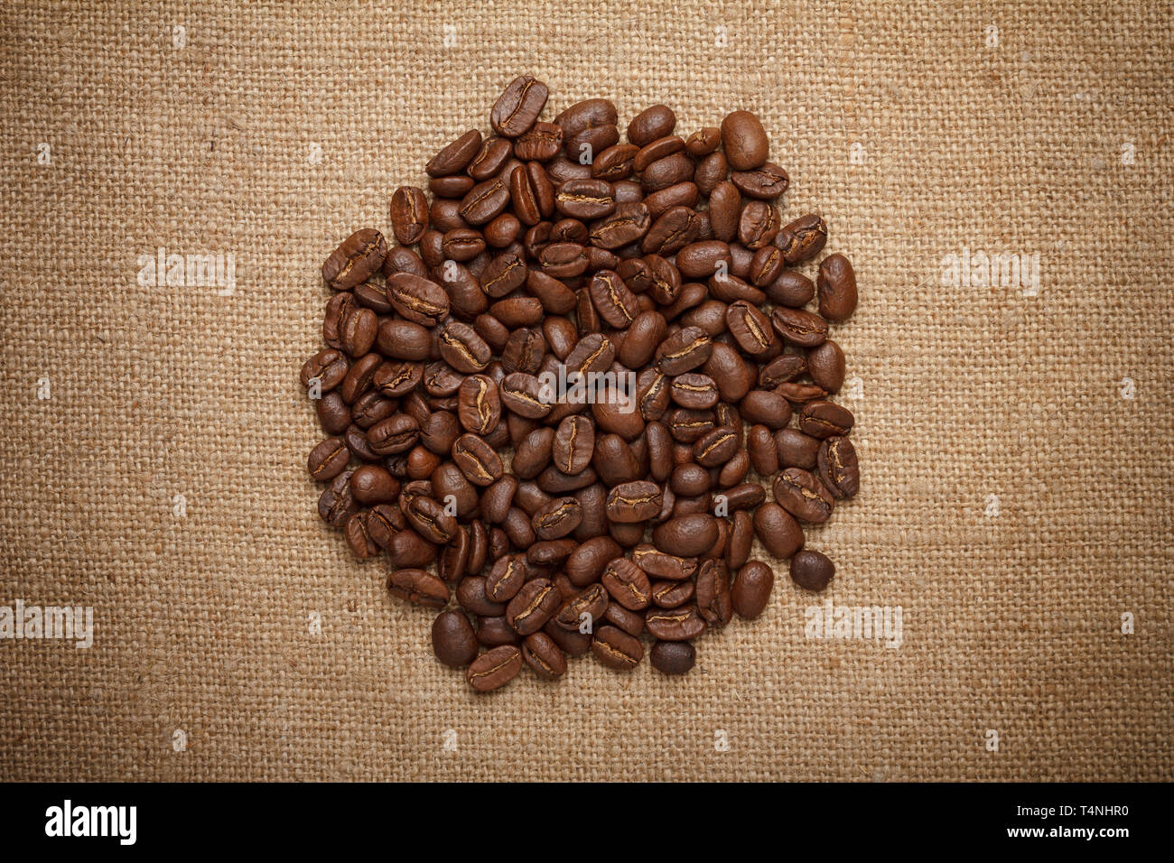 Granos de café sobre fondo de tela de saco del montón Foto de stock