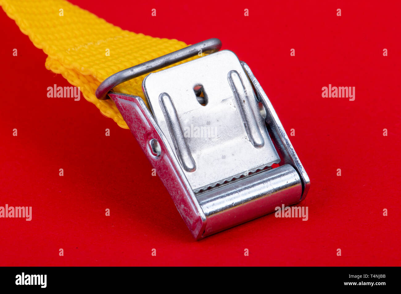 Correa de maleta amarillo con broche de metal sobre fondo rojo Fotografía  de stock - Alamy