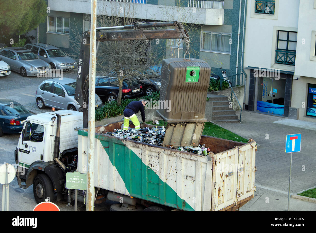 Camión camión recogiendo vidrio reciclado de botellas de vino de la papelera  de reciclaje fuera de un edificio de apartamentos en la ciudad portuguesa  de Oporto Portugal KATHY DEWITT Fotografía de stock -