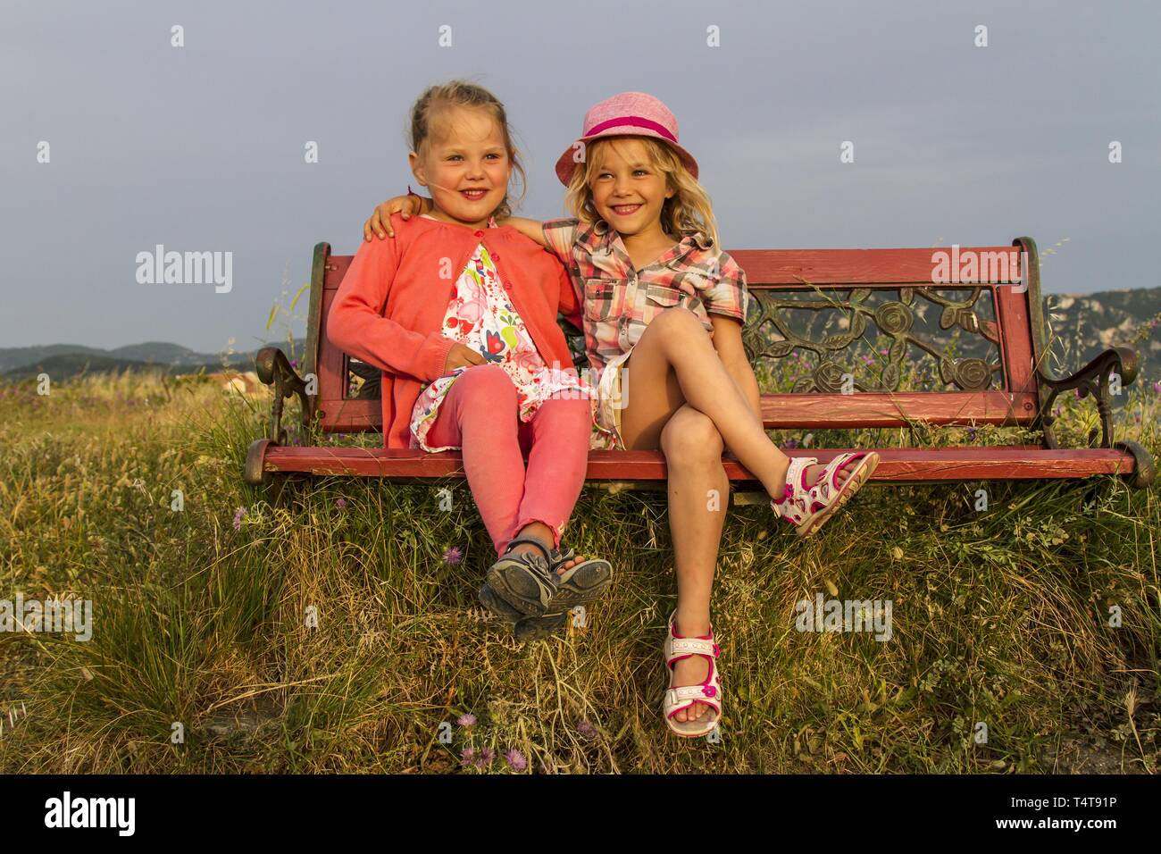 Niños (5, 6) sentado en un banco, puesta de sol, Afionas, Corfú, Grecia, Europa Foto de stock