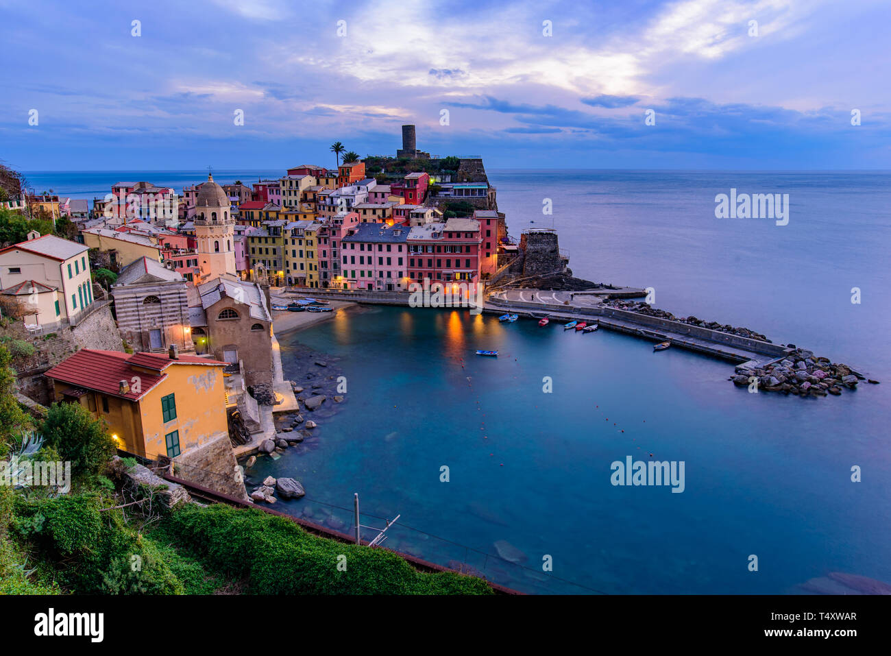 Vista de la puesta de sol de Vernazza, uno de los cinco pueblos mediterráneos en Cinque Terre, Italia, famosa por sus casas de colores y el puerto Foto de stock