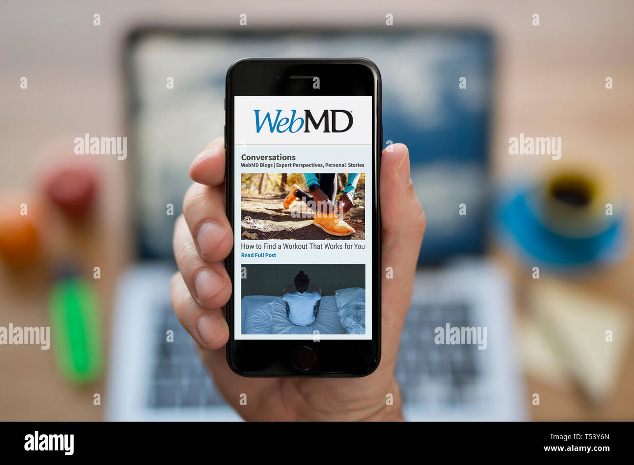 Un hombre mira el iPhone que muestra el logotipo de WebMD (uso Editorial solamente). Foto de stock