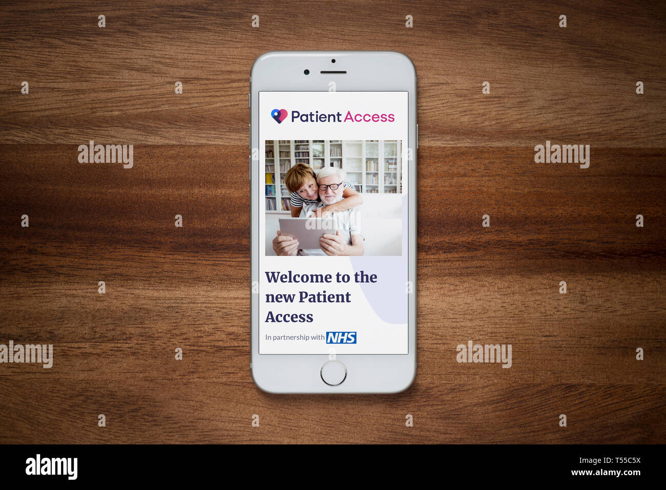 Un iPhone que muestra el sitio web de acceso del paciente descansa sobre una mesa de madera normal (uso Editorial solamente). Foto de stock