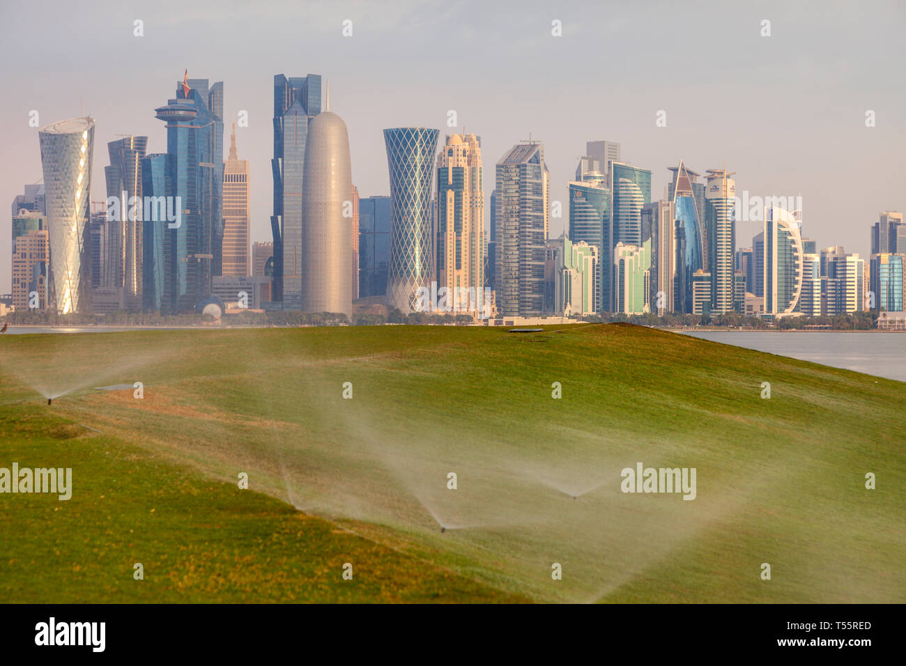 Sistema de rociadores en el césped por skyline de Doha, Qatar Foto de stock