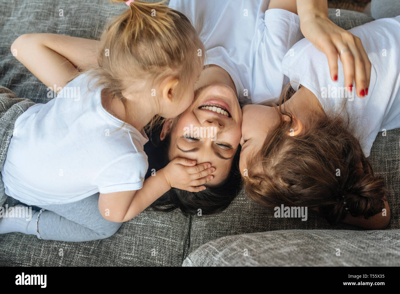 Hijas besar su mejilla de la madre Foto de stock