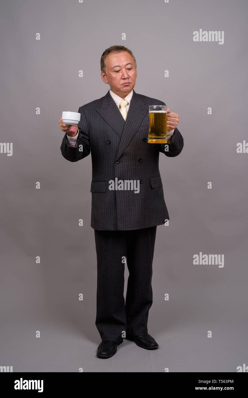 Retrato de maduro empresario asiático contra el fondo gris Foto de stock