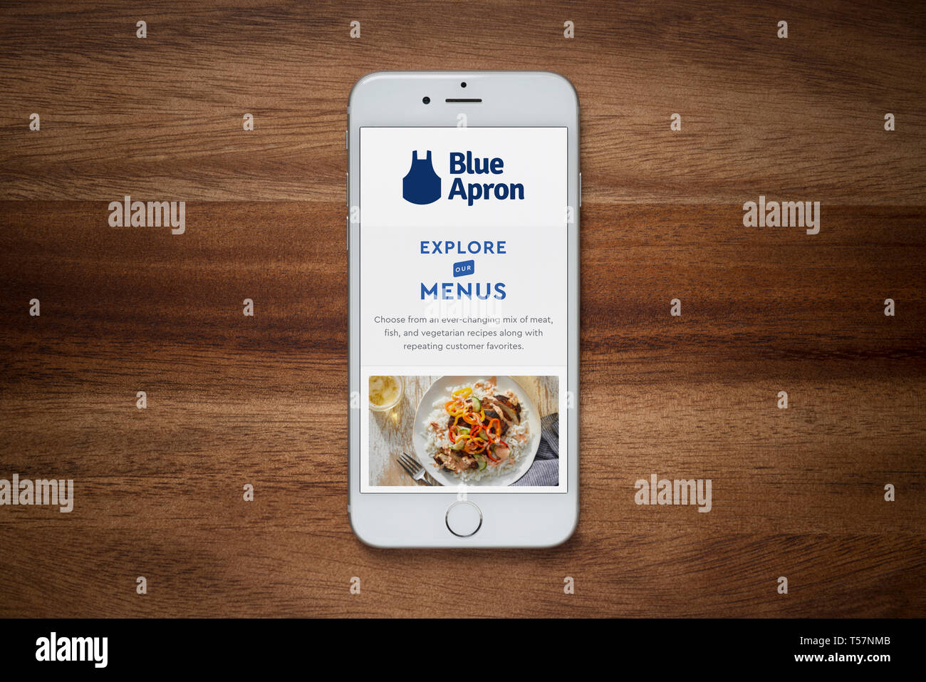Un iPhone mostrando el delantal azul website descansa sobre una mesa de madera normal (uso Editorial solamente). Foto de stock
