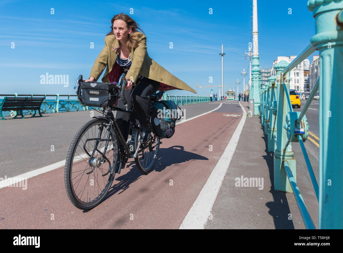 Mujer de 20 años vestida elegantemente en bicicleta a lo largo de un ciclo ruta en Brighton, East Sussex, Inglaterra, Reino Unido. Mujer inteligente en la ciclovia. Foto de stock