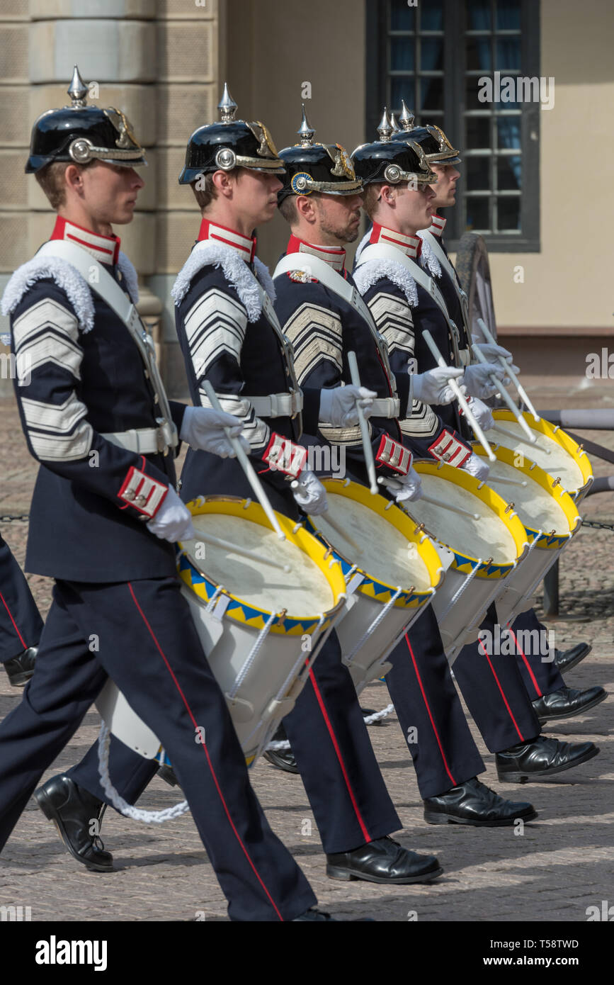 Percusionistas de la banda del Ejército Real Sueca en azul oscuro lleno de uniformes y vestido negro cascos pickelhaube desfilan durante el cambio de guardia. Foto de stock
