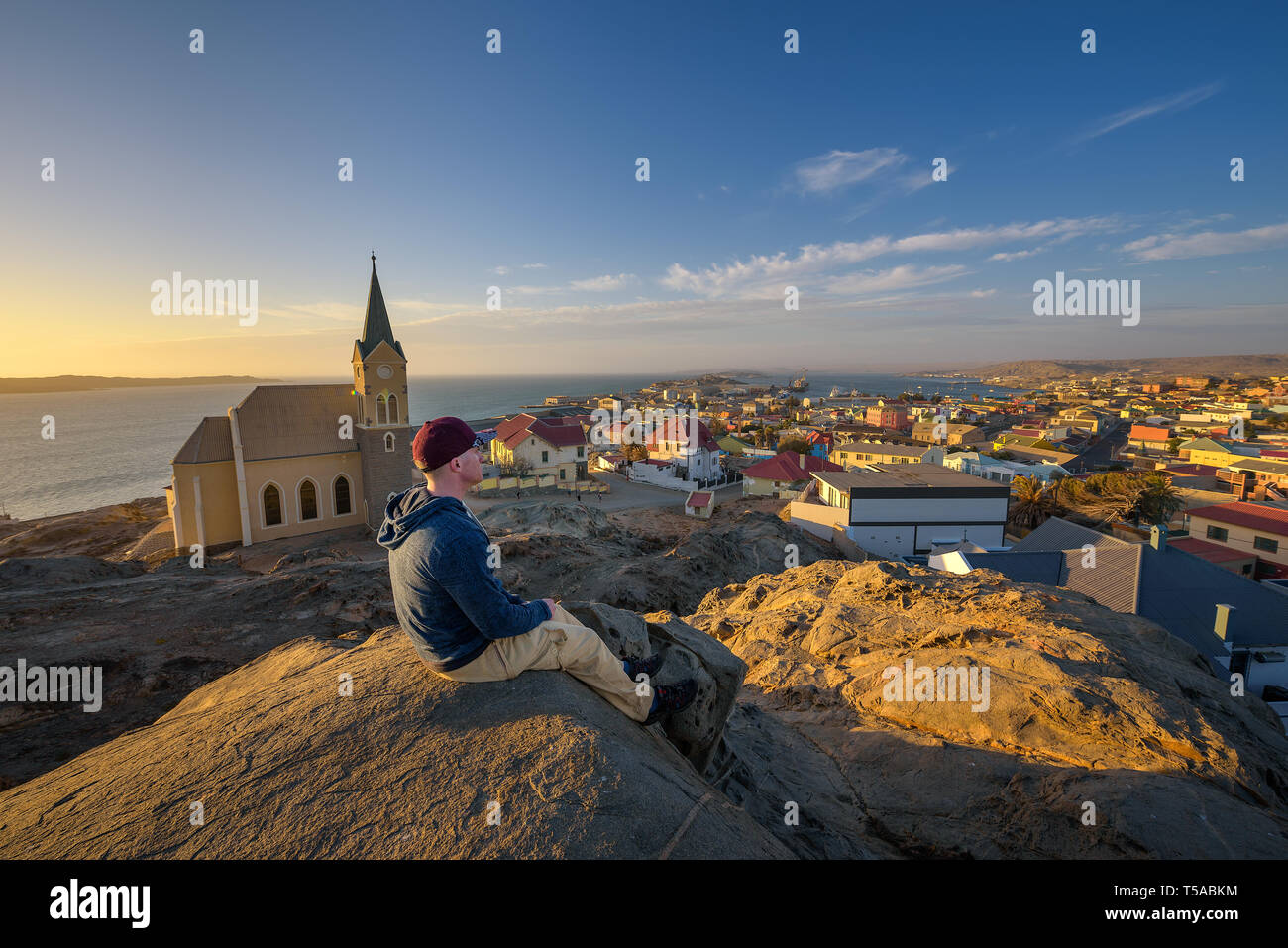 Turista en la cima de una colina, disfruta de la vista de Luderitz en Namibia al atardecer Foto de stock