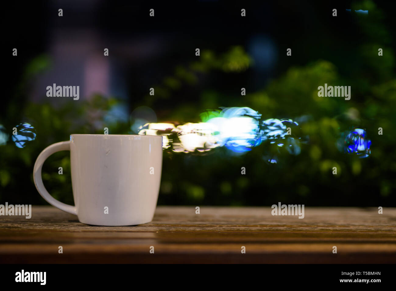 La taza de café sobre la mesa de madera en el restaurante por la noche Foto de stock