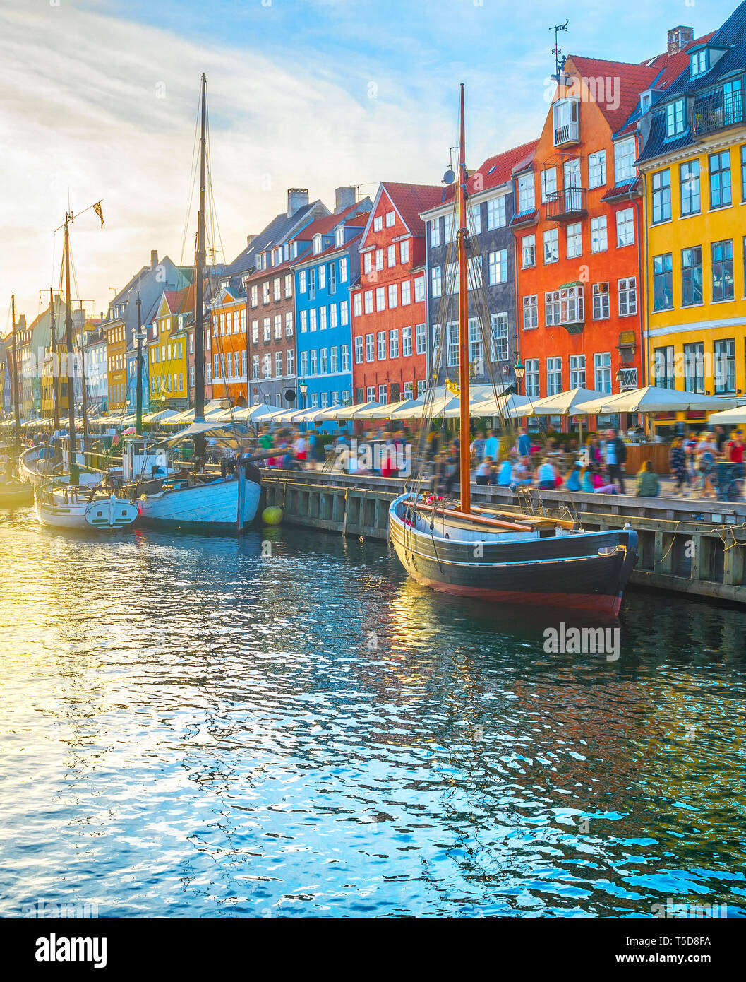 Nyhavn vista con botes por terraplén al atardecer, la gente caminar y sentarse en los restaurantes, Copenhague, Dinamarca Foto de stock