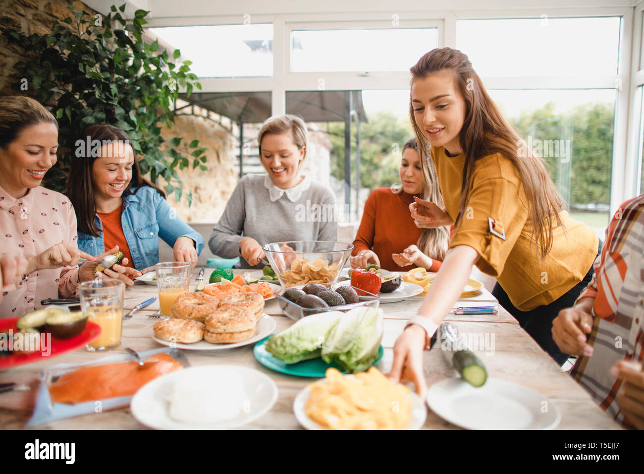 Un pequeño grupo de amigas preparan un almuerzo saludable dentro de un invernadero en una escapada de fin de semana. Foto de stock