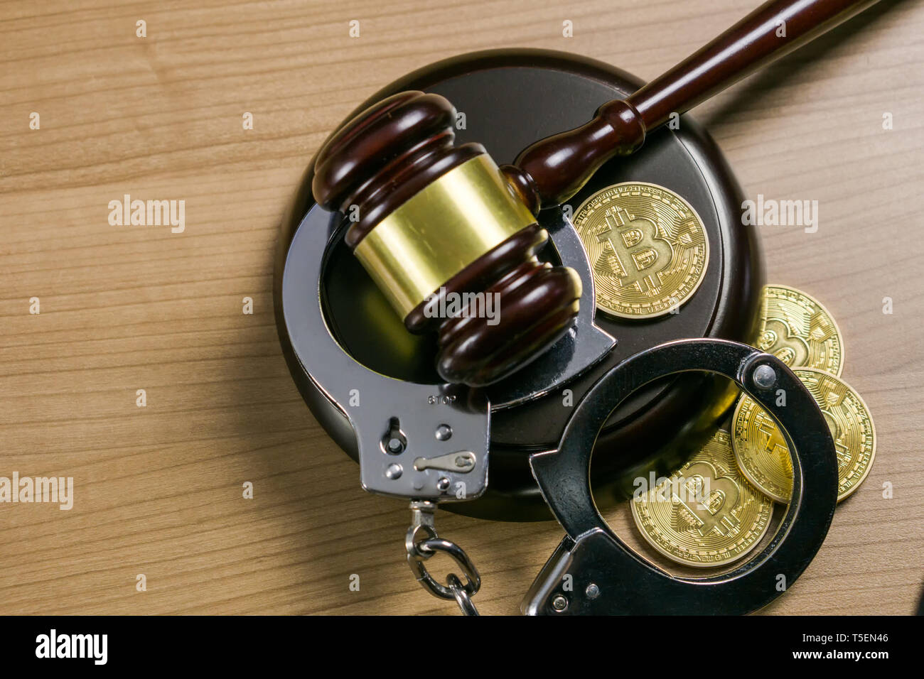 Martillo y esposas con bitcoins en un mostrador de madera. Cryptocurrency concepto jurídico. Foto de stock